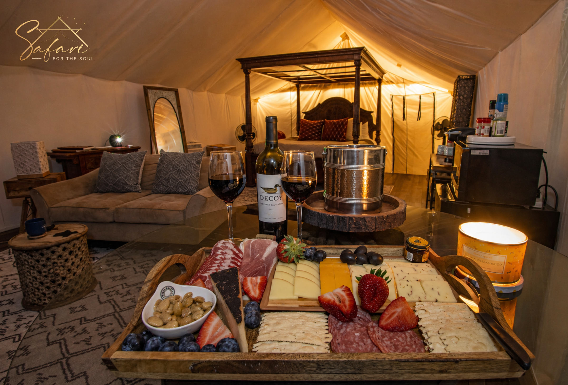Luxury charcuterie board with wine inside Tentation Yurt in Spicewood, TX featuring canopy bed, cozy sofa, and romantic glamping ambiance.
