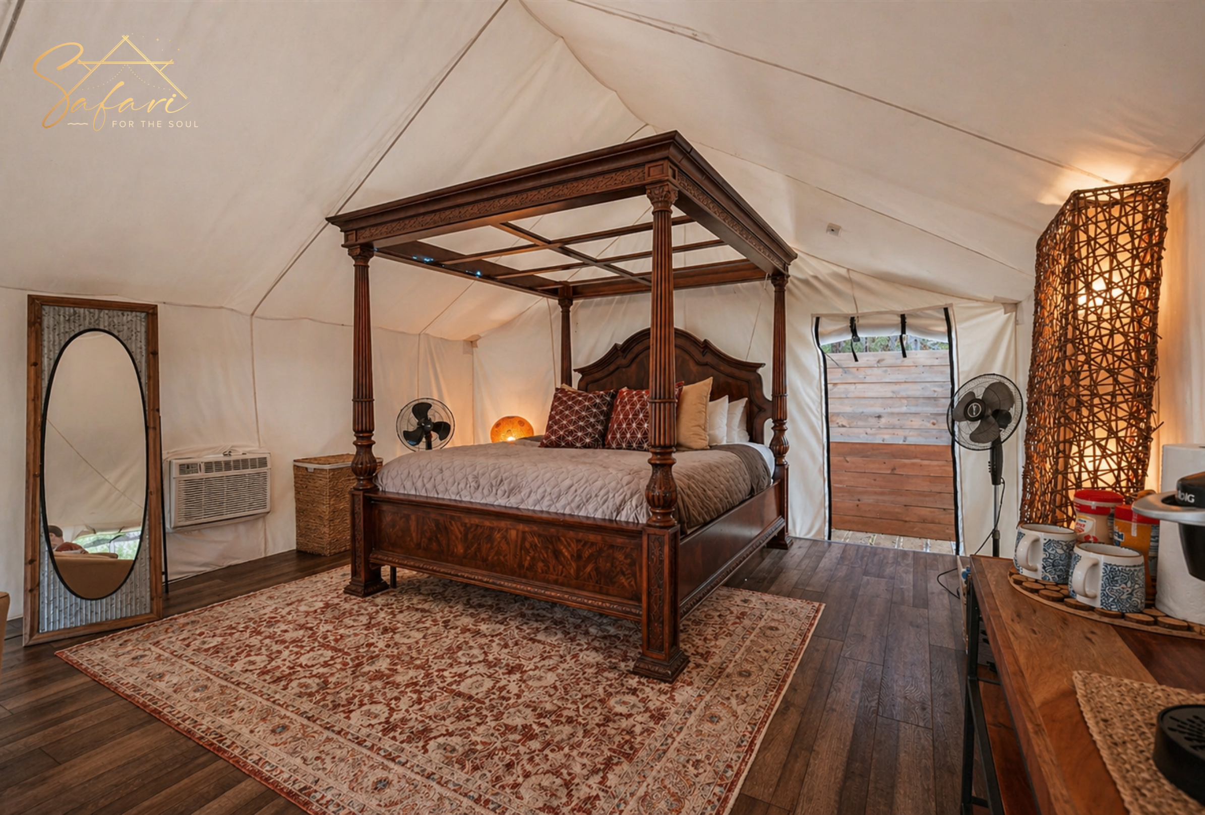 Four poster bed inside luxury glamping tent with wooden floor and cozy decor