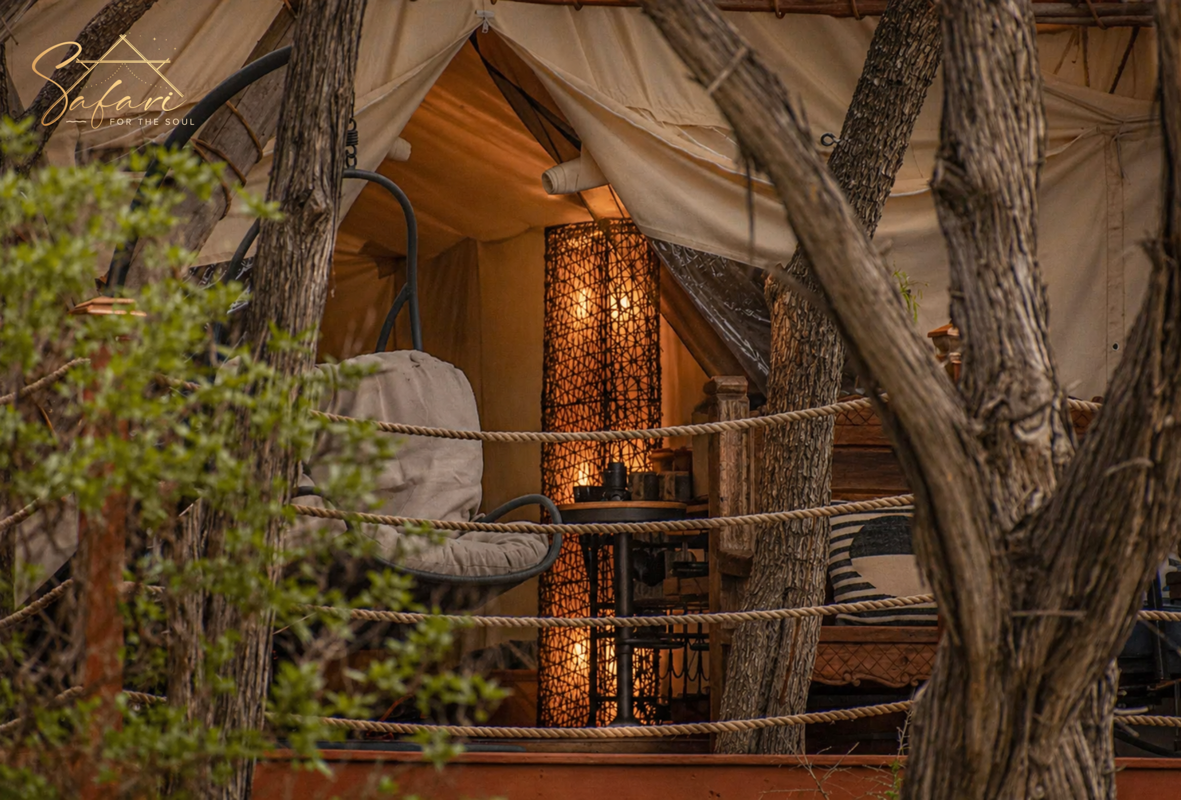 Cozy outdoor seating area on deck with warm lighting surrounded by trees at glamping site in Spicewood Texas
