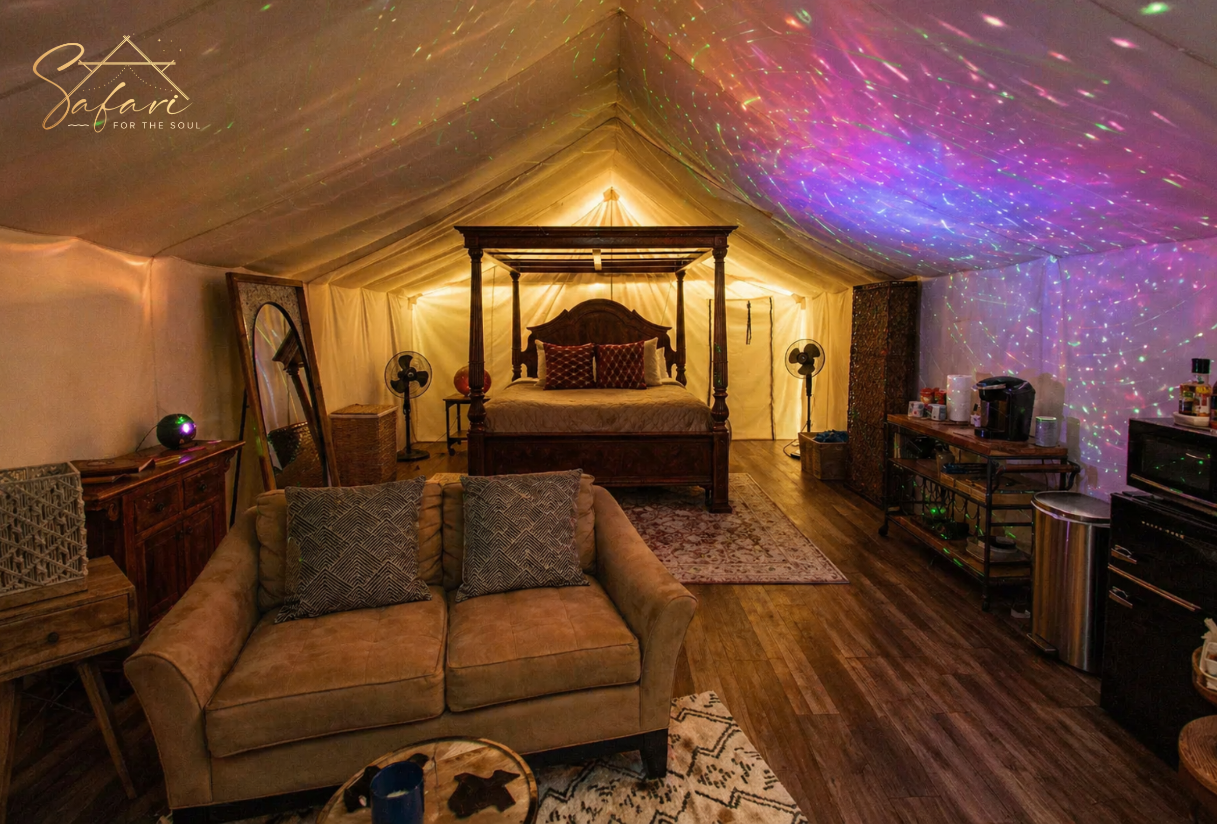 Luxury glamping tent interior with bed sofa and colorful ambient lighting in Spicewood Texas