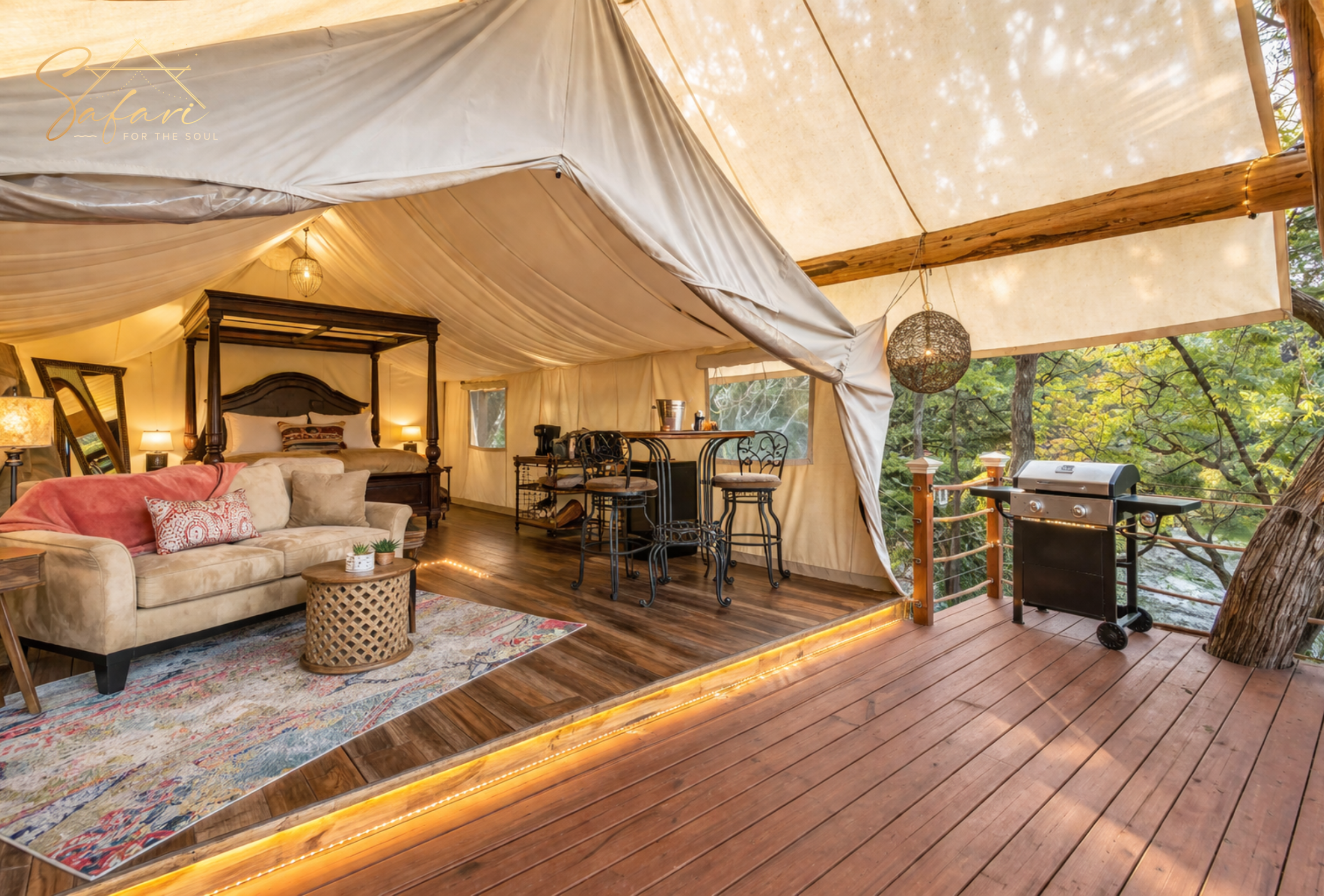 Open concept glamping tent with bed lounge area and outdoor deck with grill in Spicewood Texas