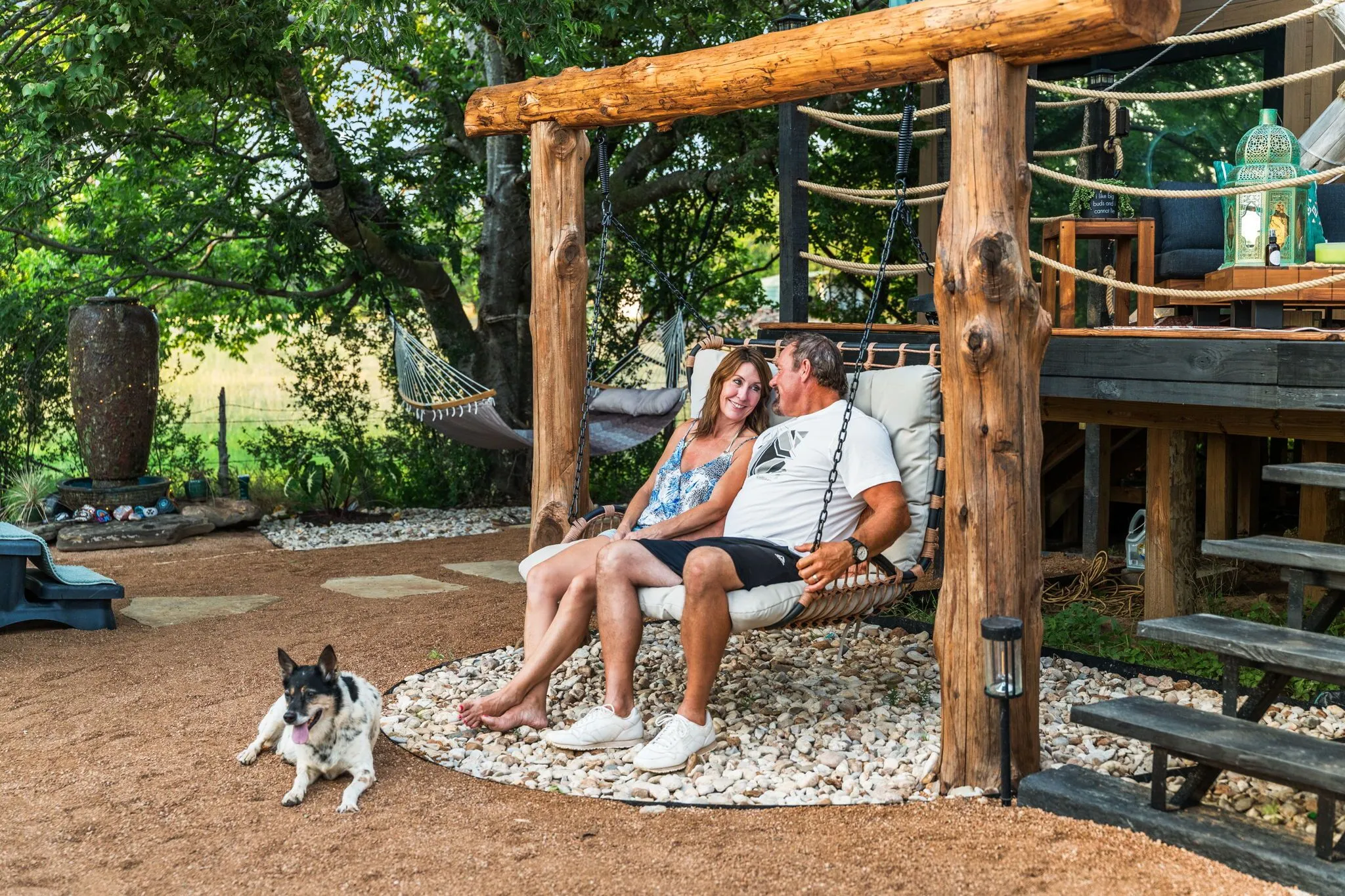 Couple relaxing on rustic swing with dog outside luxury glamping yurt in Marble Falls Texas