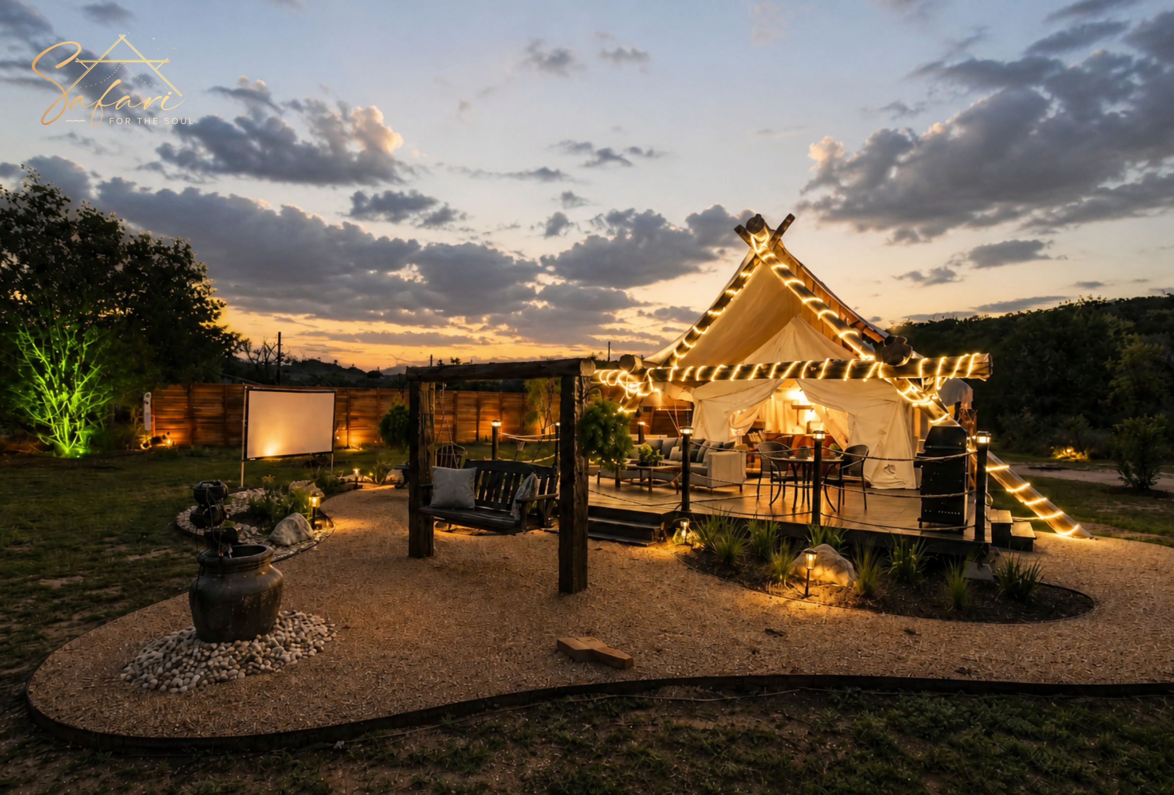 Luxury glamping tent at sunset with warm string lights, outdoor deck seating, swing bench, and ambient landscape lighting in Marble Falls Texas